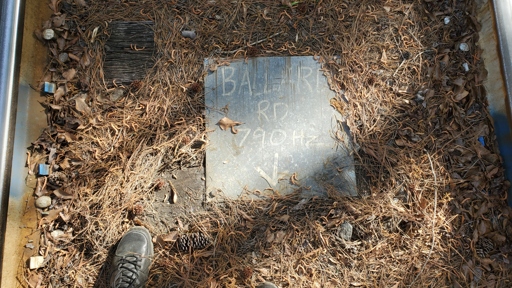 A photograph of a sign that reads "Ballard Rd 790Hz" with an arrow pointing downward.
