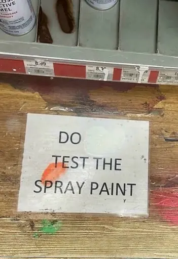 Picture of a sign saying "Do not test the spray paint", but the not has been painted over with spray paint