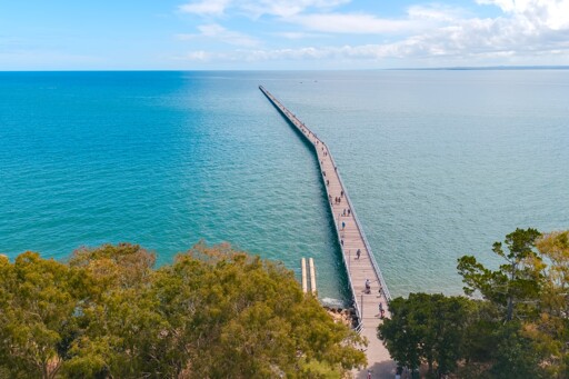An aerial drone photo, taken from the shore line, looking out along the length of the Urangan pier as it extends in to the ocean