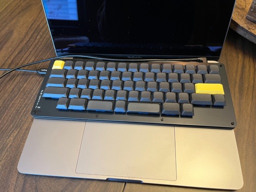 A low profile HHKB style keyboard sitting on top of a laptop.