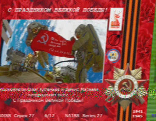 A photo of two astronauts holding a flag/poster with a hammer and sickle insignia. 